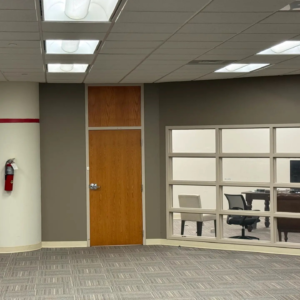 Glass-fronted private office at Tributary with a desk and guest seating