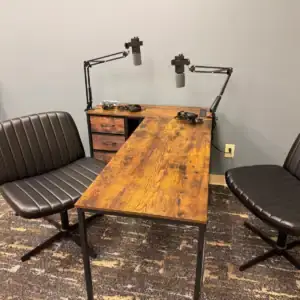 Podcast table, chairs, microphone arms, and guitar in a Tributary media room